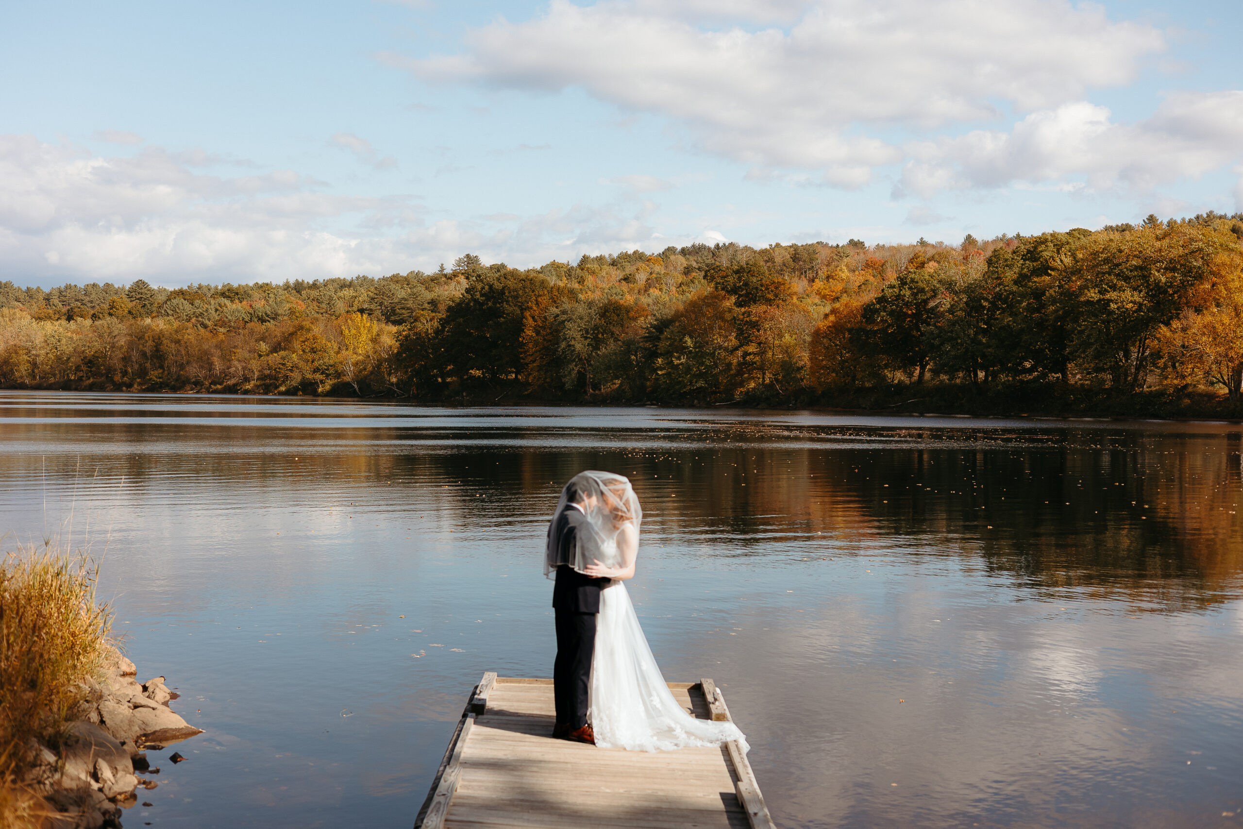 couple embracing on a secluded dock in New England during autumn.
